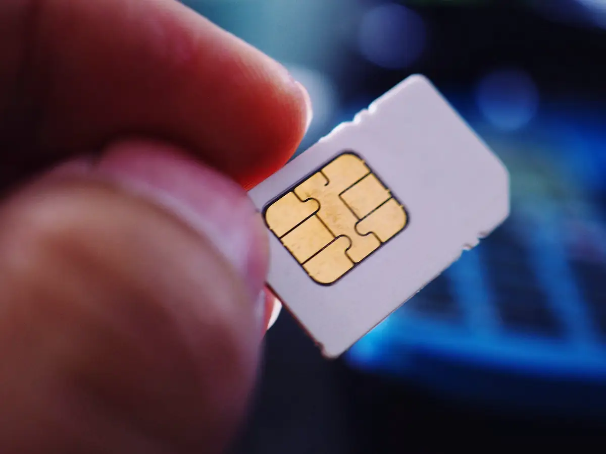 Person holding SIM card in index finger and thumb